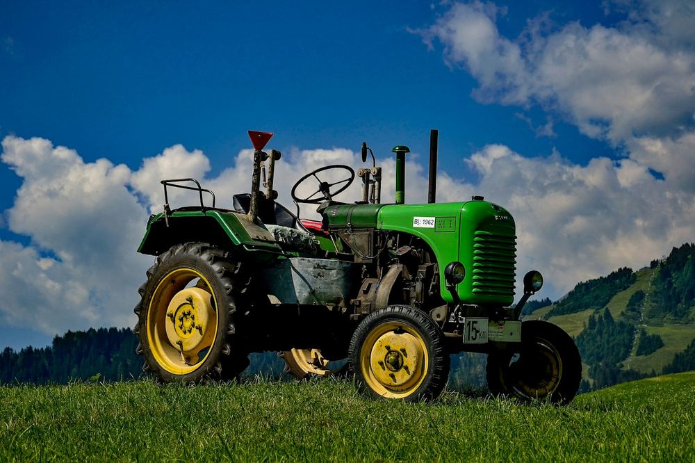 Red tractor levelling a field at sunset